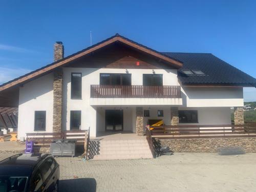 a large white house with a porch and a balcony at Pensiunea În Livada in Buneşti