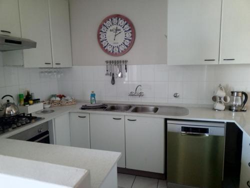 Una cocina con un fregadero y un reloj en la pared. en Beach front property, en Strand