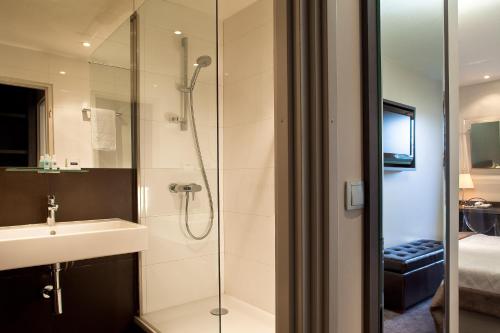 a bathroom with a shower and a sink and a mirror at Best Western Hotel Acadie Paris Nord Villepinte in Tremblay En France