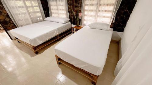 two beds in a room with white sheets at Glampyn amazonic colibri in San José del Guaviare