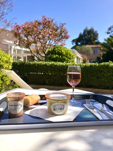 a tray with a glass of wine and a plate of food at Hôtel Jas Neuf in Sainte-Maxime