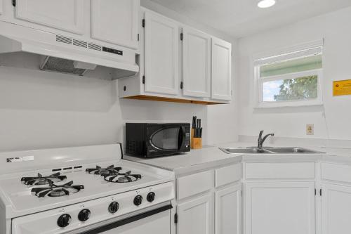 a white kitchen with a stove and a microwave at Parmer's Resort in Little Torch Key