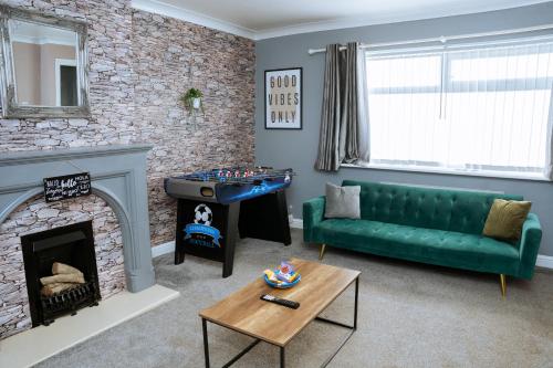 a living room with a green couch and a fireplace at Modern 3Bed Home close to Leeds City Centre in Killingbeck