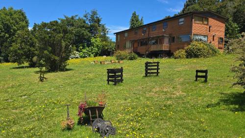 a house on a hill with chairs in the grass at Hostal Hunter in Puerto Montt