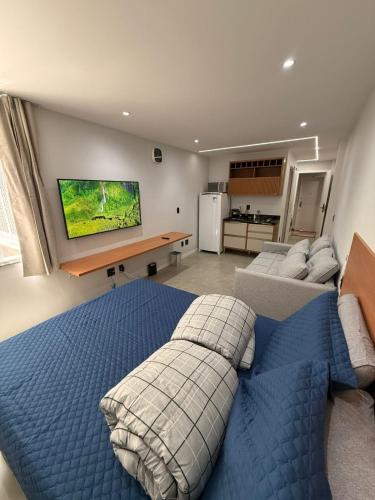 a bedroom with a blue bed and a living room at Juca Studio Botafogo in Rio de Janeiro