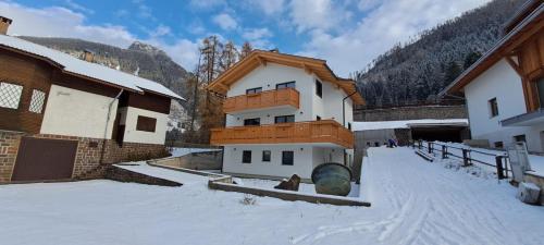 un edificio en la nieve junto a algunos edificios en Dream Apartments Moena, en Moena