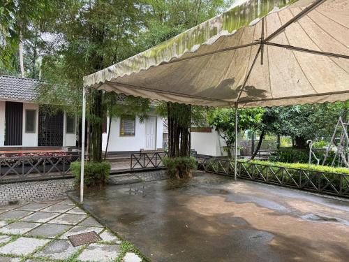 a large umbrella in front of a house at Royad Calicut Farm House - Premium Villa with Pool Inside a Farm in Kozhikode