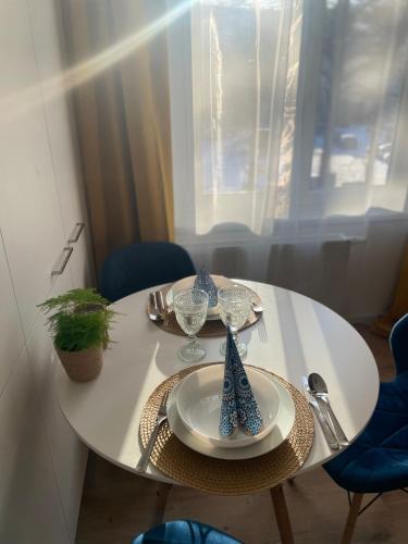 a white table with a plate and glasses on it at Labela Luhačovice Apartment in Luhačovice