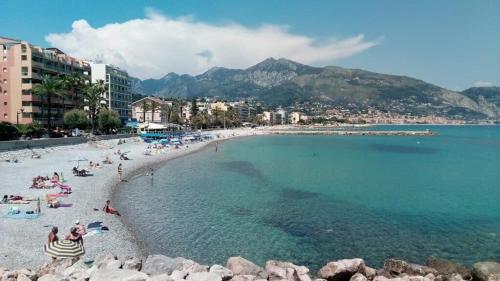 a beach with a bunch of people in the water at Studio Kialeo près de la plage avec parking voiture in Roquebrune-Cap-Martin