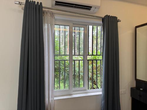 a window with black curtains in a room at Royad Calicut Farm House - Premium Villa with Pool Inside a Farm in Kozhikode