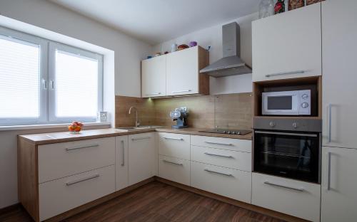 a kitchen with white cabinets and a microwave at Apartmán ACTIVE in Liptovská Kokava