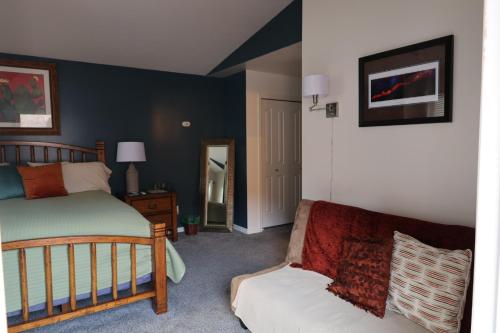 a bedroom with a bed and a couch and a mirror at Harvest House Bed and Breakfast in Springdale