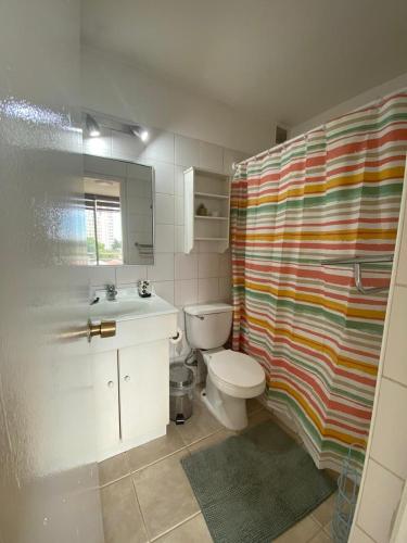 a bathroom with a toilet and a colorful shower curtain at Acogedor y amplio departamento central in Temuco