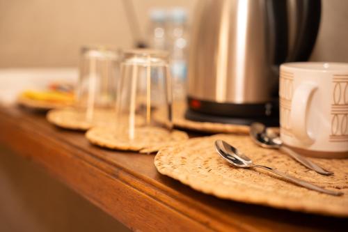 a wooden counter with plates and spoons and a coffee maker at Nomad Inn Nizwa in Nizwa