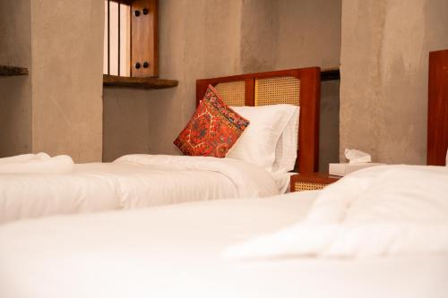 two beds with white sheets and a pillow on them at Nomad Inn Nizwa in Nizwa