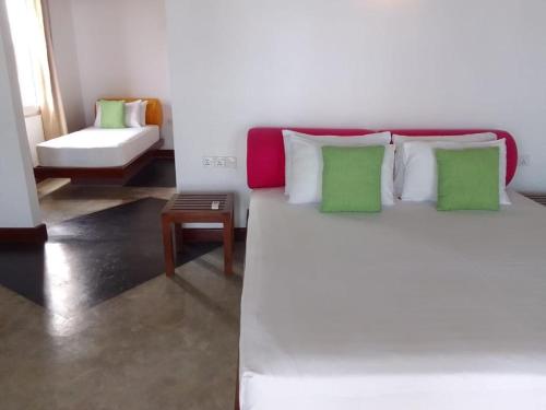 a bedroom with a large white bed with green pillows at Shavara Beach in Ahangama