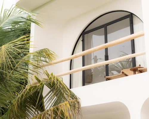 a room with a large window and a plant at Tyde Bali Boutique Hotel in Uluwatu