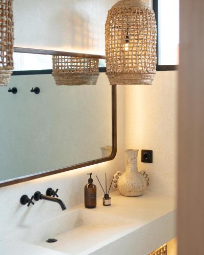 a bathroom sink with a mirror and a vase on it at Tyde Bali Boutique Hotel in Uluwatu