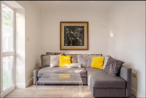 a living room with a gray couch with yellow pillows at Spacious 2BDR Apartment, WIFI+ Great TV in Romford