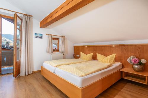 a bedroom with a bed with a wooden headboard and a window at Gästehaus Hanna Teifel in Reit im Winkl