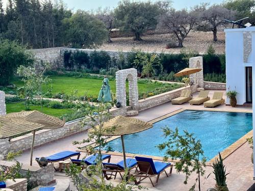 a swimming pool with chairs and umbrellas in a yard at Villa Serinie in Essaouira