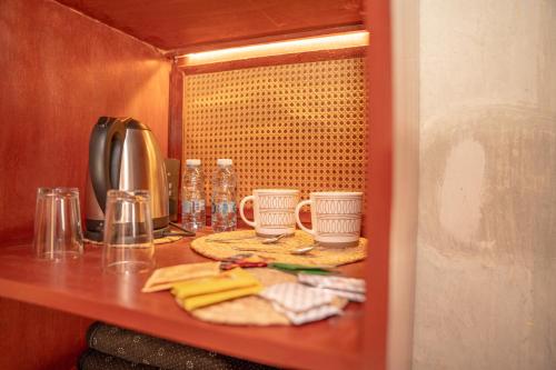 a shelf with two coffee cups and towels on it at Nomad Inn Nizwa in Nizwa