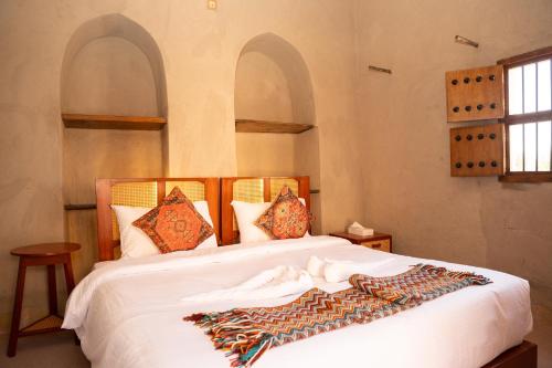a bedroom with a bed with white sheets and pillows at Nomad Inn Nizwa in Nizwa