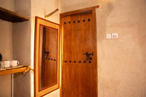 a wooden door in a room with a mirror at Nomad Inn Nizwa in Nizwa