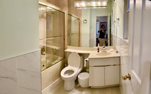 a bathroom with a toilet and a sink and a mirror at Rose Garden Vancouver in Richmond