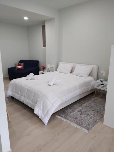 a white bedroom with a large white bed with a rug at Diacopto Country Houses in Diakopto