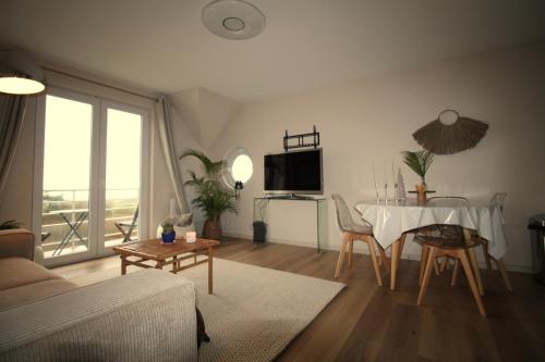 un salon avec une table et une télévision dans l'établissement appartement vue mer, à Wimereux