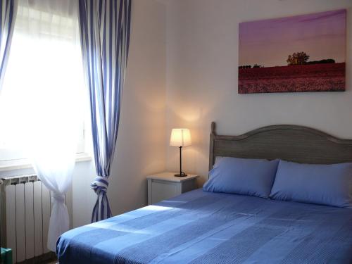 1 dormitorio con 1 cama con manta azul y ventana en Villetta Aleanto, en Mentana