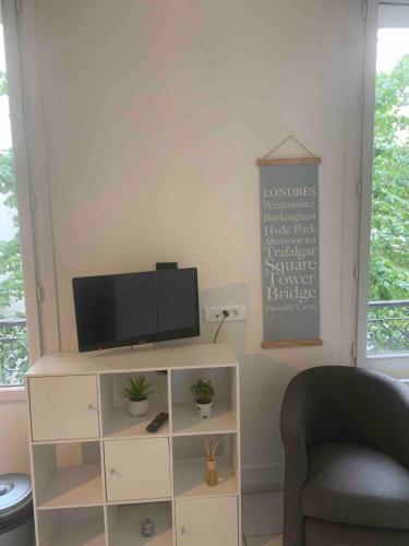 un salon avec une télévision et une chaise dans l'établissement Entire Studio - Arena La Chapelle, à Paris