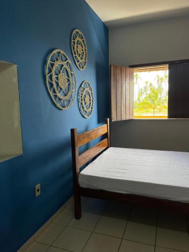 a bedroom with blue walls and a bed with plates on the wall at Casa com vista mar. Um paraíso próximo à praia! in Ilhéus