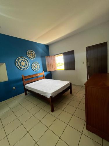 a bedroom with a bed and a blue wall at Casa com vista mar. Um paraíso próximo à praia! in Ilhéus