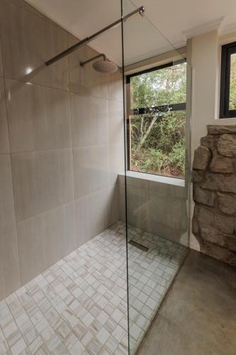 a shower with a glass door in a bathroom at Induli Lodge - Amakhala Game Reserve in Amakhala Game Reserve