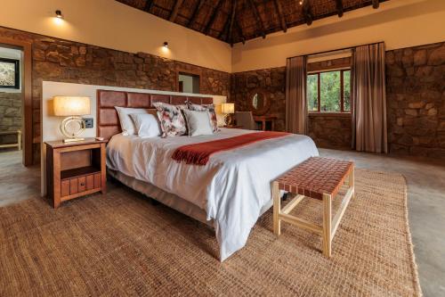 a bedroom with a large bed and a wooden wall at Induli Lodge - Amakhala Game Reserve in Amakhala Game Reserve