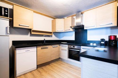 une cuisine avec des armoires en bois et un comptoir noir dans l'établissement Chalet Mouflon - 5 Pièces pour 8 Personnes MAE-1741, à Val Thorens