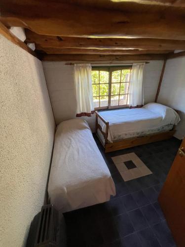 two beds in a small room with a window at Aldea Bolsón in El Bolsón