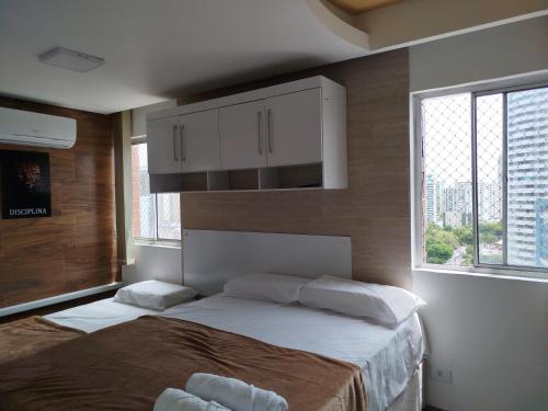 a bedroom with a large bed in a room with windows at Cobertura Duplex Vista do Mar in Recife