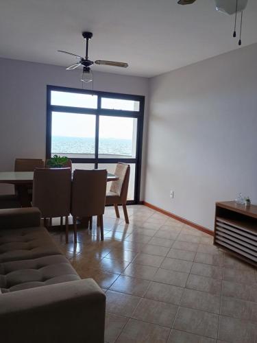 Sala de estar con mesa y sillas y vistas al océano en AP Varanda do Mar - Rio das Ostras, en Rio das Ostras