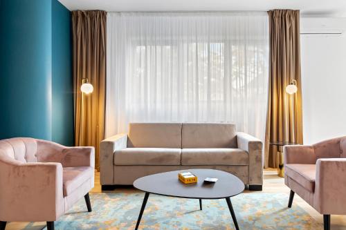 a living room with a couch and two chairs and a table at Uni88 ApartHotel in Bucharest