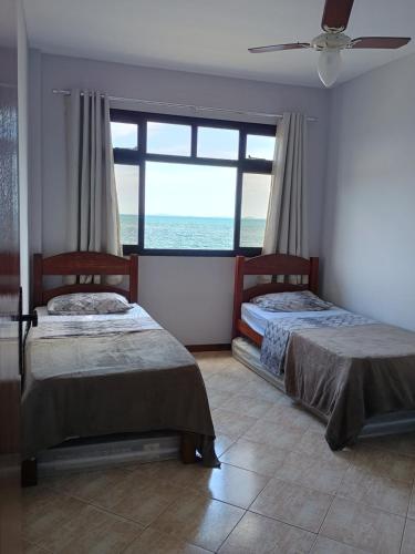 Dos camas en una habitación con vista al mar. en AP Varanda do Mar - Rio das Ostras, en Rio das Ostras