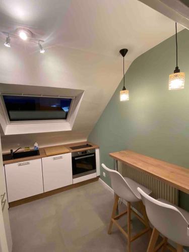 une cuisine avec des armoires blanches et une table et des chaises dans l'établissement Appartement hypercentre Colmar, à Colmar