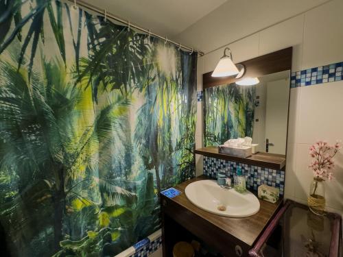 une salle de bain avec un rideau de douche tropical et un lavabo dans l'établissement Appartement familial, à 10mn de Disneyland, à Montévrain