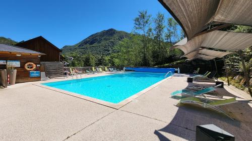 une piscine avec des chaises et une montagne en arrière-plan dans l'établissement Appartement avec balcon, Ax-Les-Thermes, à Ax-les-Thermes