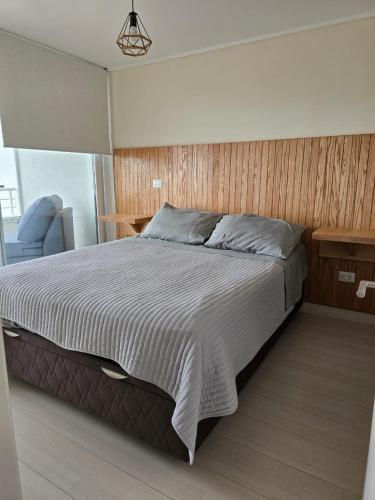 a bedroom with a large bed and a blue chair at Apartamento en Viña del Mar excelente ubicación in Viña del Mar