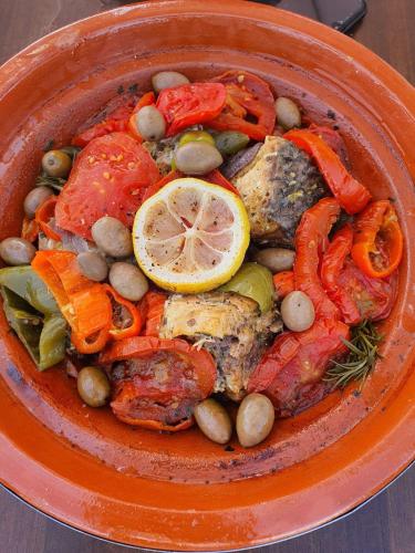 an orange bowl of food with fish and vegetables at Dar Beynana in Sidi Bibi