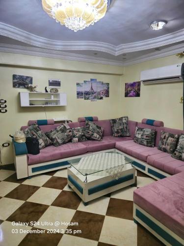 a living room with a purple couch and a chandelier at Lovely two bedrooms apartment in Asyut city in Asyut
