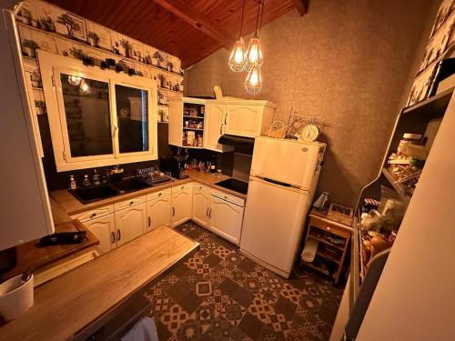 une cuisine avec des armoires blanches et un réfrigérateur blanc dans l'établissement Plain pied aux portes de La Rochelle 2chbres, à Saint-Xandre